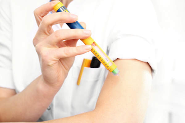 女人注射胰岛素进入臂,使用可调节的胰岛素笔。