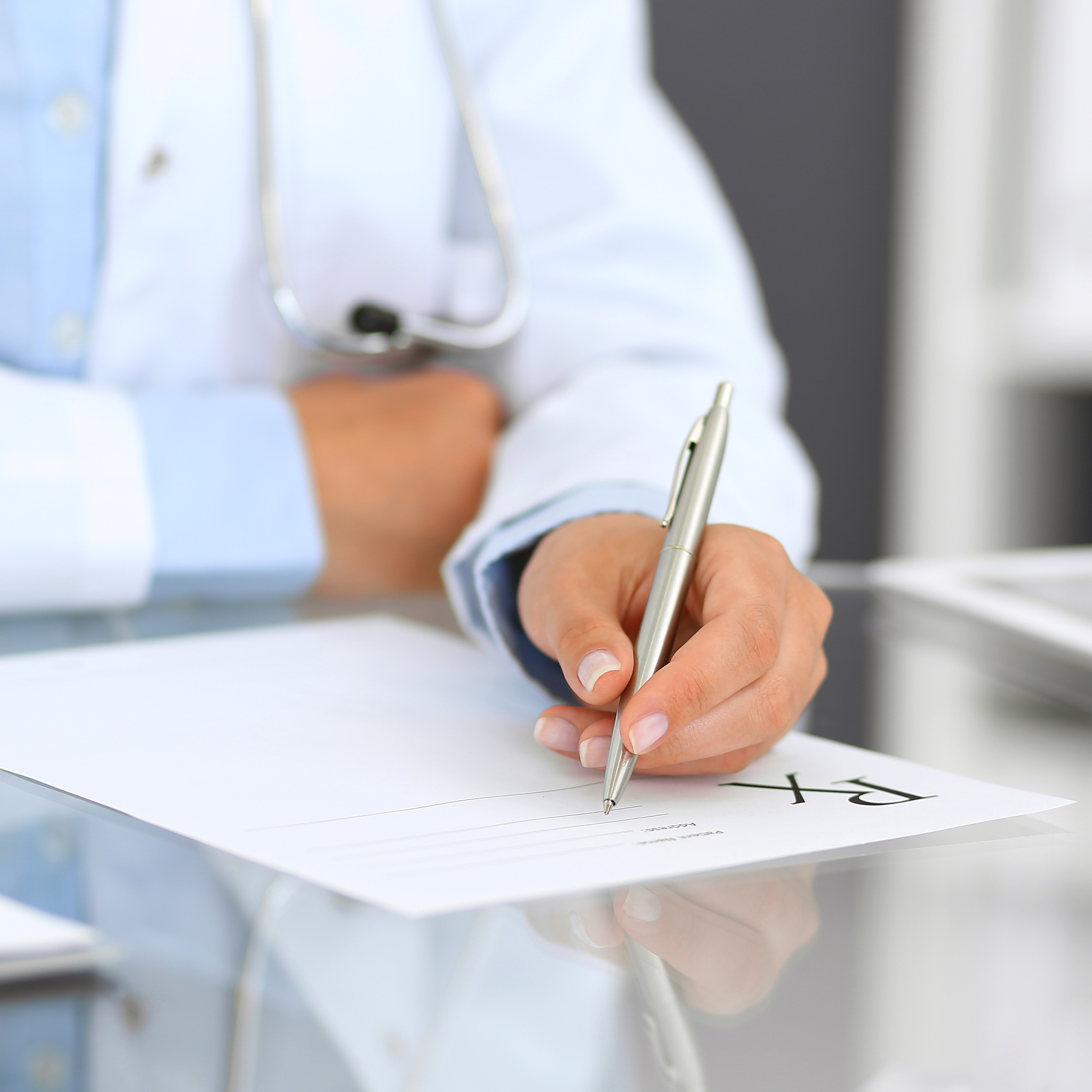 近距离医生写处方形式在医院坐在桌前。