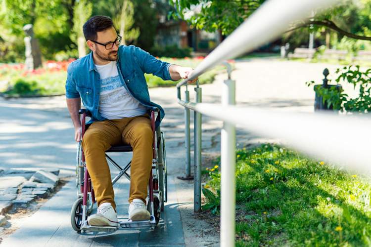 young man in manual wheelchair going up ramp