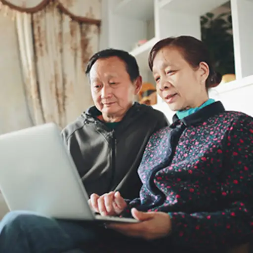 高级亚洲夫妇在家里用笔记本电脑。