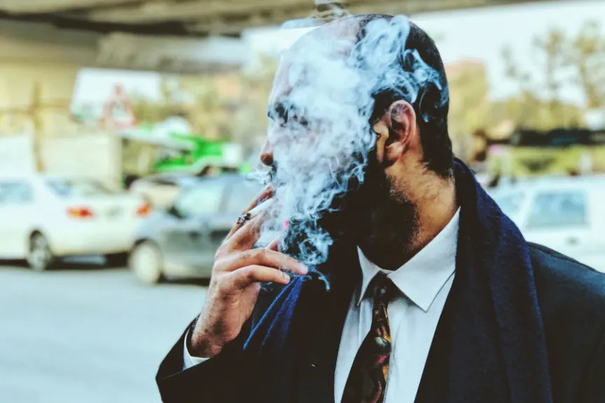 man smoking cigarette - face covered in smoke
