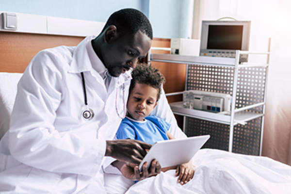 医生给躺在病床上的小男孩看药片。