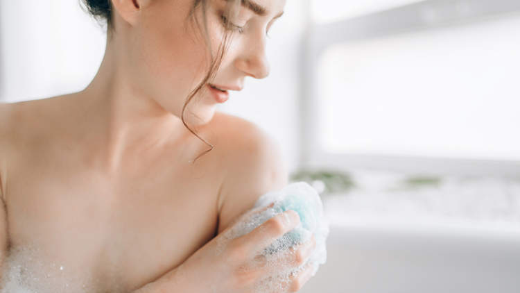 女人洗她的肩膀在淋浴。