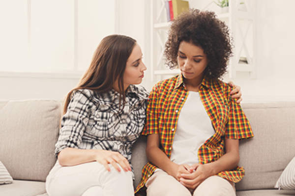 年轻女性朋友,一个提供支持的坐在沙发上。