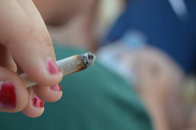 一个十几岁的女孩拿着一支大麻烟。