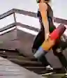 A woman holding a yoga mat walks up stairs