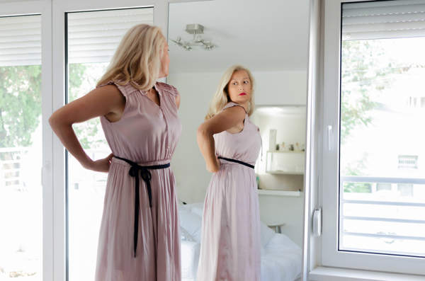 女子站在礼服在镜子前