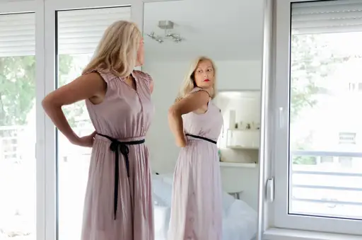 女人穿着衣服站在镜子前