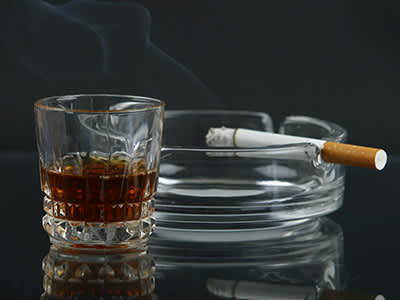 威士忌旁边在烟灰缸香烟的玻璃。