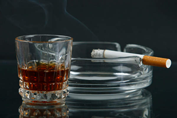 威士忌旁边在烟灰缸香烟的玻璃。