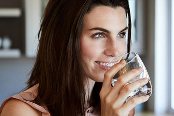 喝一杯水的微笑的少妇。