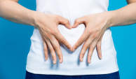 Woman with hands in shape of heart on stomach for healthy digestive tract.