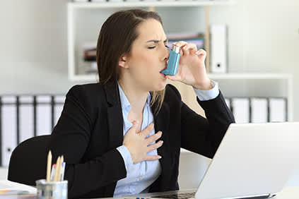 女人在办公室使用吸入器。