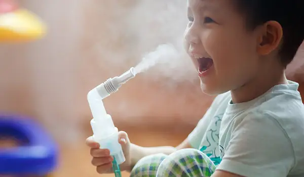 使用雾化器的愉快的小男孩哮喘的。