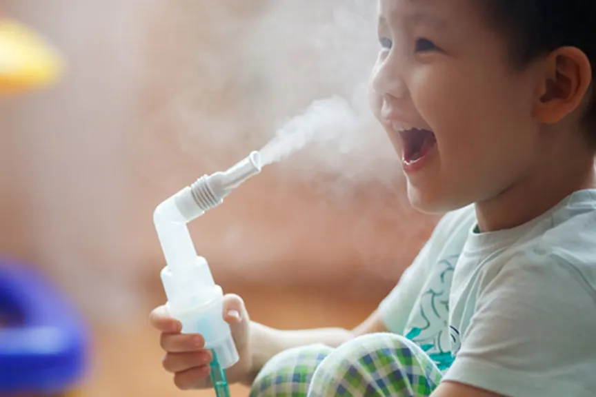 快乐的小男孩用喷雾器治疗哮喘。