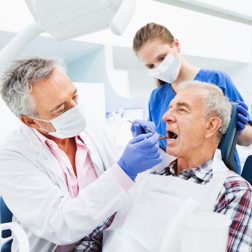 牙医和卫生员清理男人的牙齿。