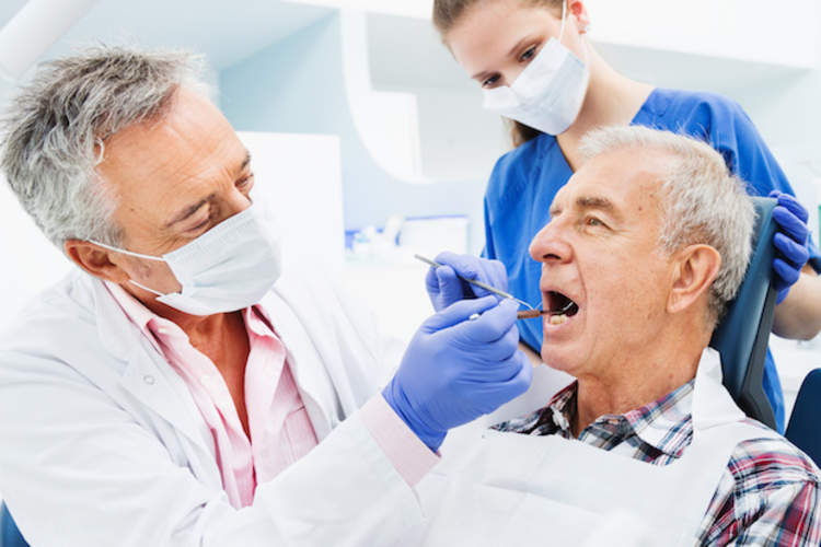 牙医和卫生员给男人清洁牙齿。