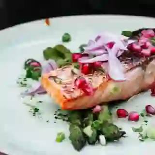 salmon on plate with pomegranate seeds and asparagus