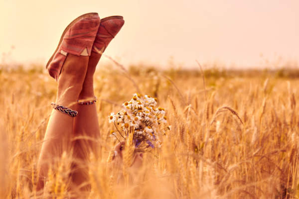 女孩手捧鲜花，躺在麦田里，穿着舒适的鞋子