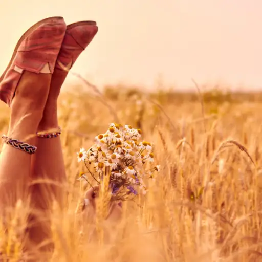 女孩手捧鲜花，躺在麦田里，穿着舒适的鞋子