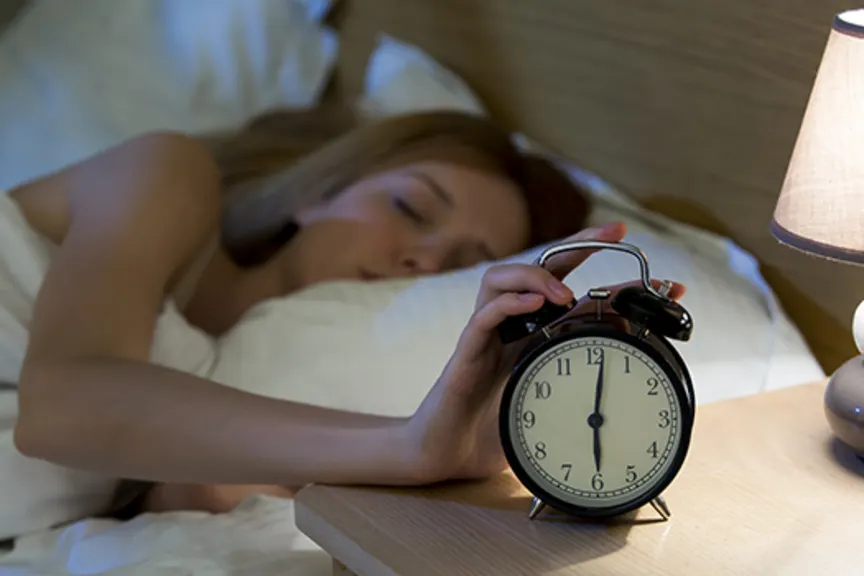 女人睡在床上，触摸闹钟。