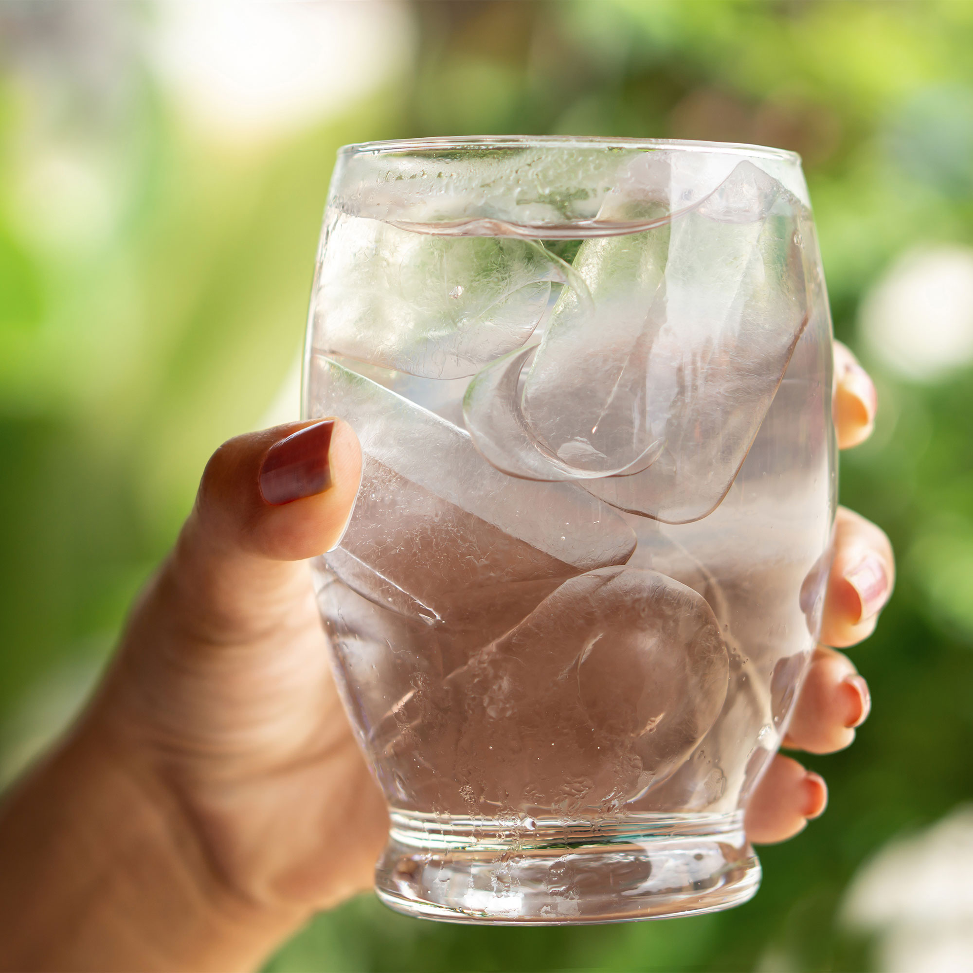 一个女人的特写镜头，拿着一杯水和冰