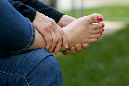 女子抱着脚，脚痛概念。