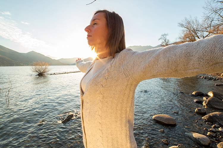 由湖有权的女人张开双臂。
