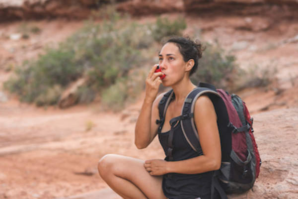 女性徒步旅行者停下来使用吸入器。