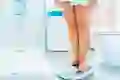 A view of a woman’s legs standing on a scale in a bathroom