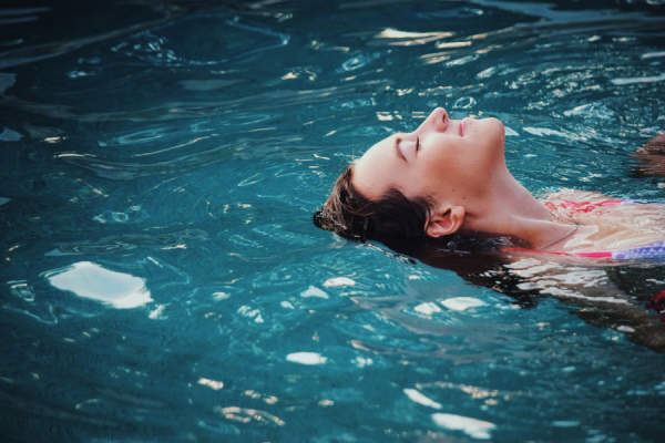 女人闭着眼睛，在泳池里放松