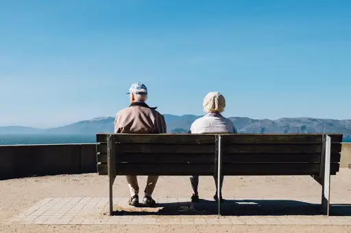 老夫妇坐在长椅上，望着远方