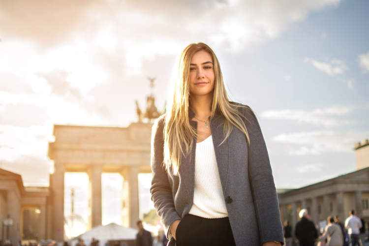 德国柏林，时尚的年轻女子在勃兰登堡门前微笑。