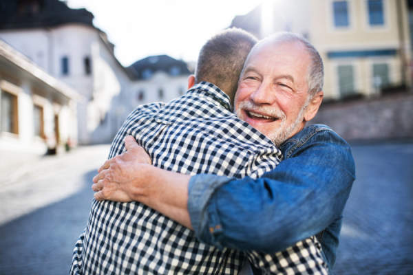 一个时髦的成年儿子和他年长的父亲在镇上拥抱。