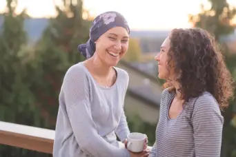 妇女战斗癌症和穿头裹裹在门廊上的姐妹谈话