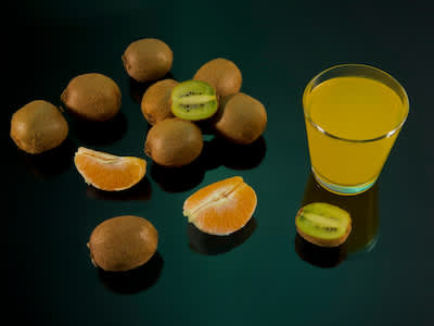 在黑色背景上放上橙汁和猕猴桃，再配上一杯猕猴桃汁。