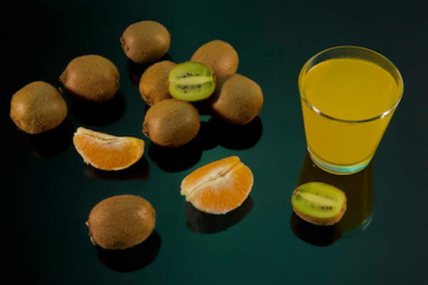 在黑色背景上放上橙汁和猕猴桃,再配上一杯猕猴桃汁。