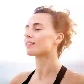 A woman closes her eyes and meditates outside