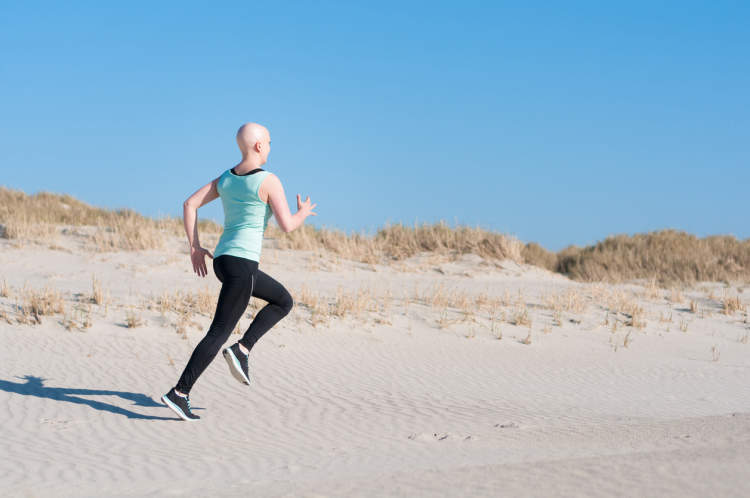 一名妇女在接受癌症治疗期间在海滩上慢跑。