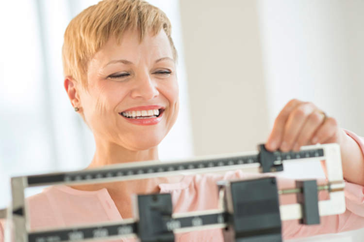 一位快乐的女性在称体重时微笑着。