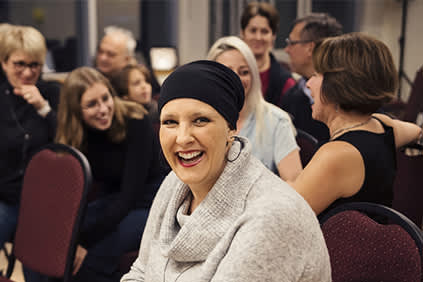 微笑的女人被支持的癌症社区包围。