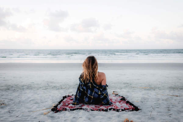 女人独自坐在沙滩上看着大海
