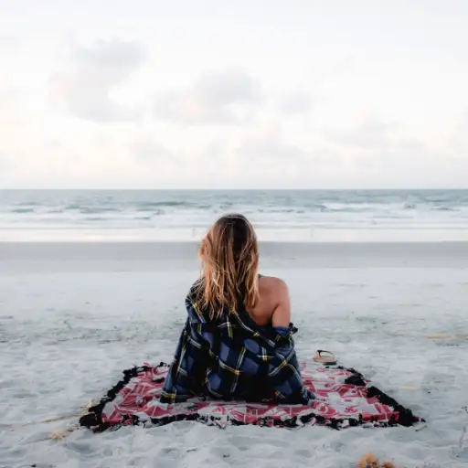 一个女人独自坐在沙滩上看大海