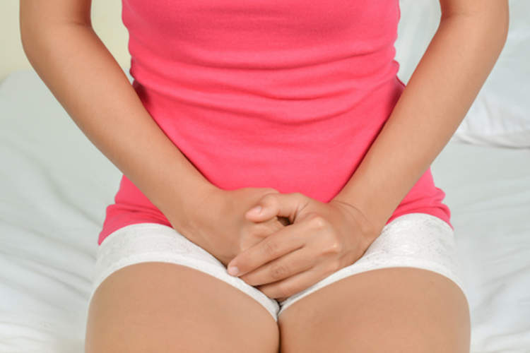 女人坐在床边,痛经。