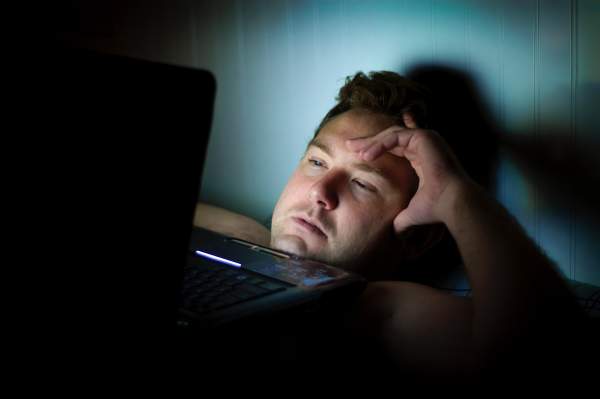 男人晚上躺在床上看电脑