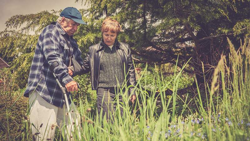 老人,中风幸存者,行走在他成年的女儿的树林拐杖。