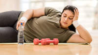 休息在与重量的锻炼期间的超重妇女。