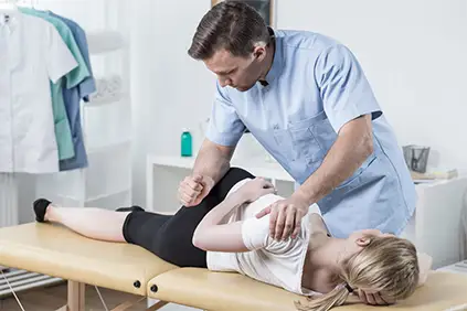 理疗师为年轻女性做脊柱推拿。