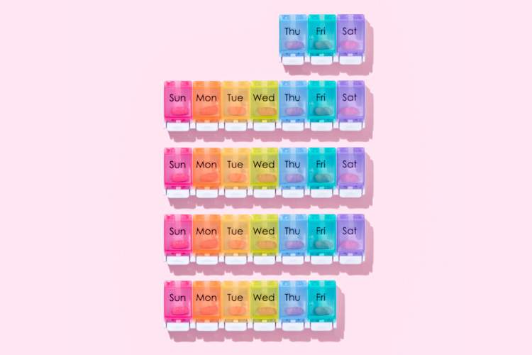 彩色每月药丸容器粉红色的背景