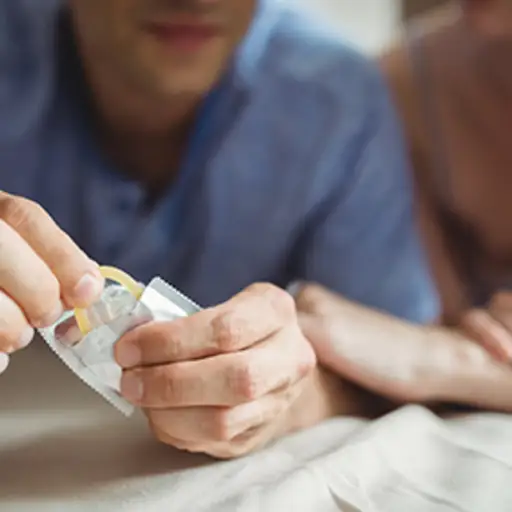 Couple opening a condom wrapper.